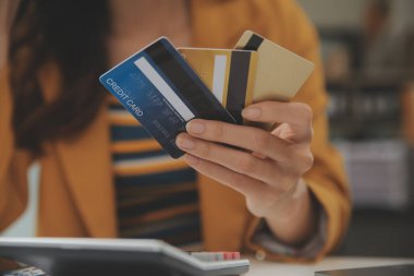 Evde kredi kartı tutan ve akıllı telefonlar kullanan kadınlar. Çevrimiçi alışveriş, internet bankacılığı, çevrimiçi mağaza, ödeme, harcama parası, e-ticaret ödemesi, kredi kartı, konsept