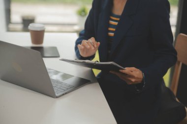 Asyalı iş kadını dizüstü bilgisayar kullanıyor ve ofiste hesap makinesi ile çalışıyor, mali raporu, iş planı yatırımını, mali analiz konseptini analiz etmeyi planlıyor..