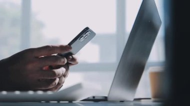 Genç adam evdeki modern ofiste dizüstü bilgisayar kullanıyor..