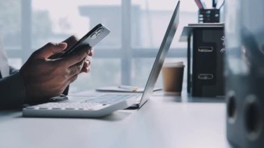 Genç adam kullanarak dizüstü bilgisayarda çalışırken Smartphone