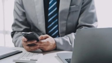 Ofisteki iş yerinde akıllı telefon kullanan bir işadamı.