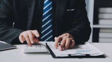 İşadamı, ofisteki mali belgeleri hesaplamak için hesap makinesi kullanıyor