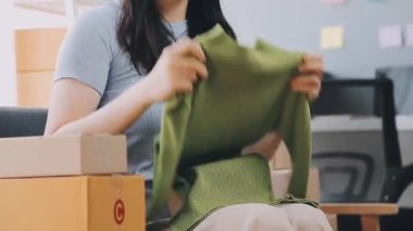 Genç Asyalı kadın teslimat için karton kutular paketliyor.