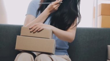 Asyalı kadın evinde paket kutusu paketliyor. dağıtım hizmeti ve online alışveriş konsepti.