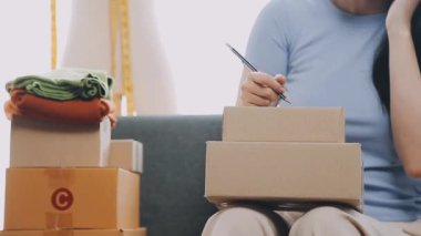 Yeni eşyaları müşteriye teslim etmek için karton kutu paketleyen bir kadın..