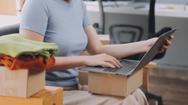Üniformalı teslimatçı elinde bir paket tutuyor ve bilgisayar kullanıyor. çevrimiçi dağıtım kavramı.