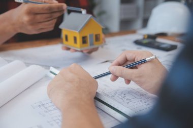 İnşaat mühendisi Asyalı 'nın ofis masasındaki inşaat sahasında mimari tasarım projesi üzerinde çalışmasını kapatın..