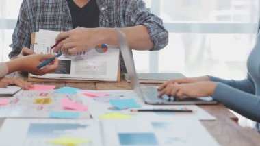 Genç iş adamı ve kadın modern ofiste yeni projeleri tartışıyor ve grafikleri gösteriyor.