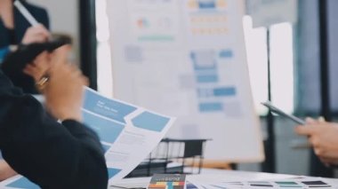 Genç Asyalı iş kadını grafiği tutuyor ve işaret ediyor. İş ekibi toplantı odasında..