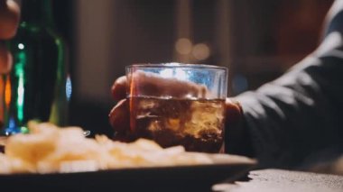 Bir bardak viskiyi elinde tutan bir adam..