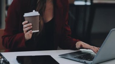 Ofisteki kafede dizüstü bilgisayarda çalışan genç bir iş kadını.