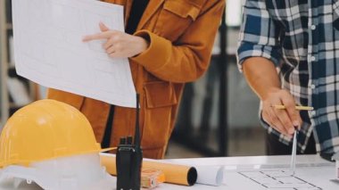 Yakın plan - iş yerindeki masanın üzerinde miğferli ve planlı işçiyle erkek eli.