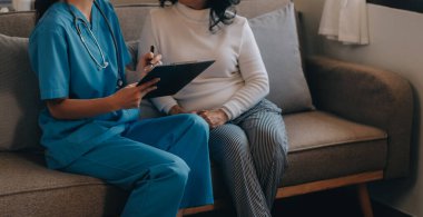 Asyalı doktor kadın, teşhis koymak ve evdeki ya da özel hastanedeki sağlığı kontrol etmek için hasta kadını ziyaret etti. Kadın hasta, sağlık sorununu ve belirtileri doktorlara açıklar.