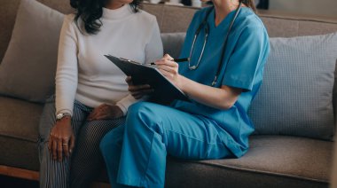 Asyalı doktor kadın, teşhis koymak ve evdeki ya da özel hastanedeki sağlığı kontrol etmek için hasta kadını ziyaret etti. Kadın hasta, sağlık sorununu ve belirtileri doktorlara açıklar.