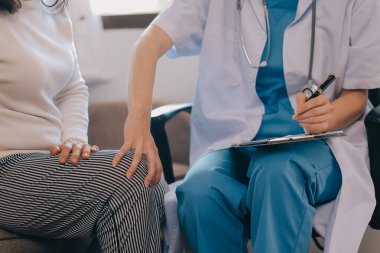 Asyalı doktor kadın, teşhis koymak ve evdeki ya da özel hastanedeki sağlığı kontrol etmek için hasta kadını ziyaret etti. Kadın hasta, sağlık sorununu ve belirtileri doktorlara açıklar.