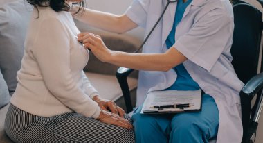 Asyalı doktor kadın, teşhis koymak ve evdeki ya da özel hastanedeki sağlığı kontrol etmek için hasta kadını ziyaret etti. Kadın hasta, sağlık sorununu ve belirtileri doktorlara açıklar.