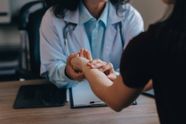 Asyalı doktor kadın, teşhis koymak ve evdeki ya da özel hastanedeki sağlığı kontrol etmek için hasta kadını ziyaret etti. Kadın hasta, sağlık sorununu ve belirtileri doktorlara açıklar.