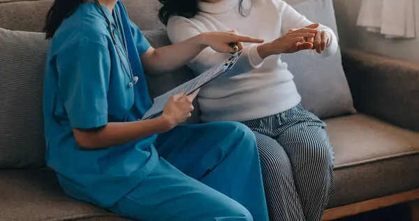 Asian doctor woman visited patient woman to diagnosis and check up health at home or private hospital. Female patient explain health problem and symptoms to doctor .Health care premium service at home