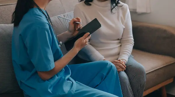 Asian doctor woman visited patient woman to diagnosis and check up health at home or private hospital. Female patient explain health problem and symptoms to doctor .Health care premium service at home