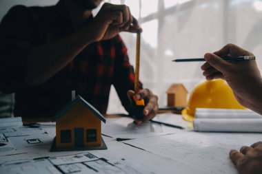 İnşaat mühendisi Asyalı 'nın ofis masasındaki inşaat sahasında mimari tasarım projesi üzerinde çalışmasını kapatın..