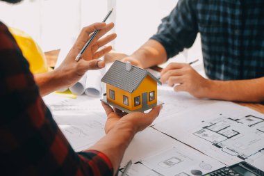 İnşaat mühendisi Asyalı 'nın ofis masasındaki inşaat sahasında mimari tasarım projesi üzerinde çalışmasını kapatın..