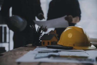 İnşaat mühendisi Asyalı 'nın ofis masasındaki inşaat sahasında mimari tasarım projesi üzerinde çalışmasını kapatın..