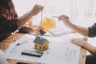 İnşaat mühendisi Asyalı 'nın ofis masasındaki inşaat sahasında mimari tasarım projesi üzerinde çalışmasını kapatın..