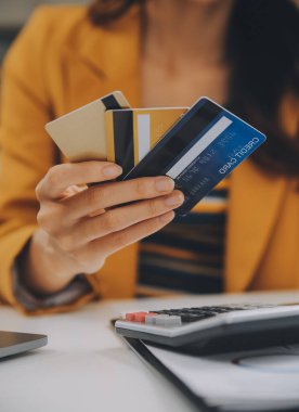 Evde kredi kartı tutan ve akıllı telefonlar kullanan kadınlar. Çevrimiçi alışveriş, internet bankacılığı, çevrimiçi mağaza, ödeme, harcama parası, e-ticaret ödemesi, kredi kartı, konsept