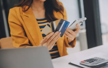 Evde kredi kartı tutan ve akıllı telefonlar kullanan kadınlar. Çevrimiçi alışveriş, internet bankacılığı, çevrimiçi mağaza, ödeme, harcama parası, e-ticaret ödemesi, kredi kartı, konsept