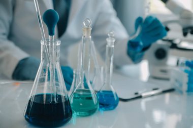 Coronavirus aşısı geliştirmek için mikroskop ile çalışan biyokimyasal araştırma ekibi farmasötik araştırma laboratuvarında, seçici odaklı