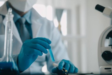 Coronavirus aşısı geliştirmek için mikroskop ile çalışan biyokimyasal araştırma ekibi farmasötik araştırma laboratuvarında, seçici odaklı