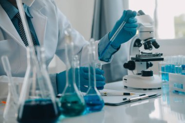 Coronavirus aşısı geliştirmek için mikroskop ile çalışan biyokimyasal araştırma ekibi farmasötik araştırma laboratuvarında, seçici odaklı