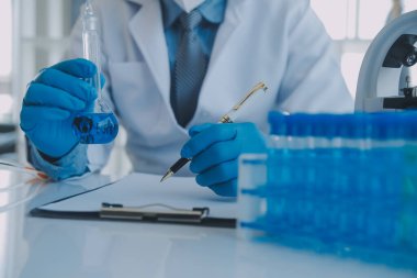 Coronavirus aşısı geliştirmek için mikroskop ile çalışan biyokimyasal araştırma ekibi farmasötik araştırma laboratuvarında, seçici odaklı