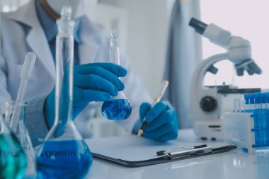 Coronavirus aşısı geliştirmek için mikroskop ile çalışan biyokimyasal araştırma ekibi farmasötik araştırma laboratuvarında, seçici odaklı