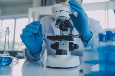 Coronavirus aşısı geliştirmek için mikroskop ile çalışan biyokimyasal araştırma ekibi farmasötik araştırma laboratuvarında, seçici odaklı