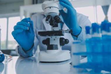 Coronavirus aşısı geliştirmek için mikroskop ile çalışan biyokimyasal araştırma ekibi farmasötik araştırma laboratuvarında, seçici odaklı