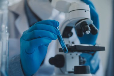 Coronavirus aşısı geliştirmek için mikroskop ile çalışan biyokimyasal araştırma ekibi farmasötik araştırma laboratuvarında, seçici odaklı
