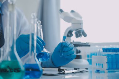 Coronavirus aşısı geliştirmek için mikroskop ile çalışan biyokimyasal araştırma ekibi farmasötik araştırma laboratuvarında, seçici odaklı