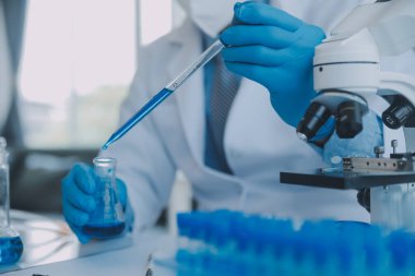 Coronavirus aşısı geliştirmek için mikroskop ile çalışan biyokimyasal araştırma ekibi farmasötik araştırma laboratuvarında, seçici odaklı