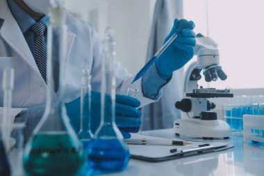 Coronavirus aşısı geliştirmek için mikroskop ile çalışan biyokimyasal araştırma ekibi farmasötik araştırma laboratuvarında, seçici odaklı