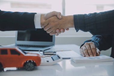 Kapalı Asyalı erkek araba satıcısı ya da satış müdürü bir araba satmayı teklif ediyor ve bir araba sözleşmesi ve sigorta sözleşmesi imzalama şartlarını açıklıyor..