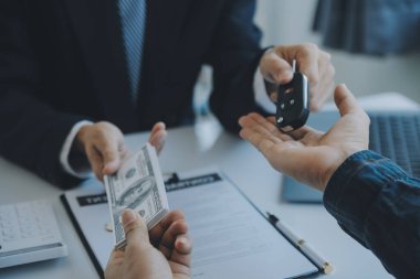 Kapalı Asyalı erkek araba satıcısı ya da satış müdürü bir araba satmayı teklif ediyor ve bir araba sözleşmesi ve sigorta sözleşmesi imzalama şartlarını açıklıyor..