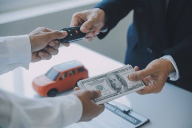 Kapalı Asyalı erkek araba satıcısı ya da satış müdürü bir araba satmayı teklif ediyor ve bir araba sözleşmesi ve sigorta sözleşmesi imzalama şartlarını açıklıyor..