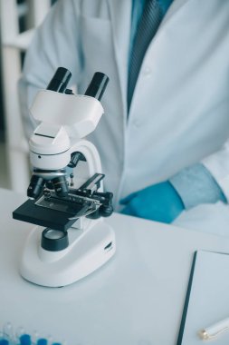 Coronavirus aşısı geliştirmek için mikroskop ile çalışan biyokimyasal araştırma ekibi farmasötik araştırma laboratuvarında, seçici odaklı