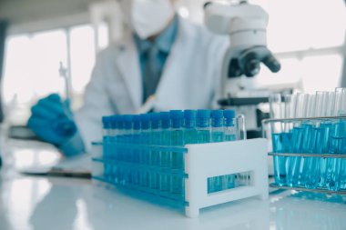 Coronavirus aşısı geliştirmek için mikroskop ile çalışan biyokimyasal araştırma ekibi farmasötik araştırma laboratuvarında, seçici odaklı