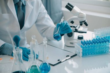Coronavirus aşısı geliştirmek için mikroskop ile çalışan biyokimyasal araştırma ekibi farmasötik araştırma laboratuvarında, seçici odaklı