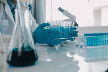 Coronavirus aşısı geliştirmek için mikroskop ile çalışan biyokimyasal araştırma ekibi farmasötik araştırma laboratuvarında, seçici odaklı