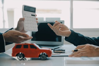 Kapalı Asyalı erkek araba satıcısı ya da satış müdürü bir araba satmayı teklif ediyor ve bir araba sözleşmesi ve sigorta sözleşmesi imzalama şartlarını açıklıyor..