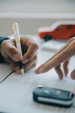Kapalı Asyalı erkek araba satıcısı ya da satış müdürü bir araba satmayı teklif ediyor ve bir araba sözleşmesi ve sigorta sözleşmesi imzalama şartlarını açıklıyor..