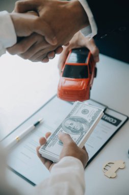 Kapalı Asyalı erkek araba satıcısı ya da satış müdürü bir araba satmayı teklif ediyor ve bir araba sözleşmesi ve sigorta sözleşmesi imzalama şartlarını açıklıyor..